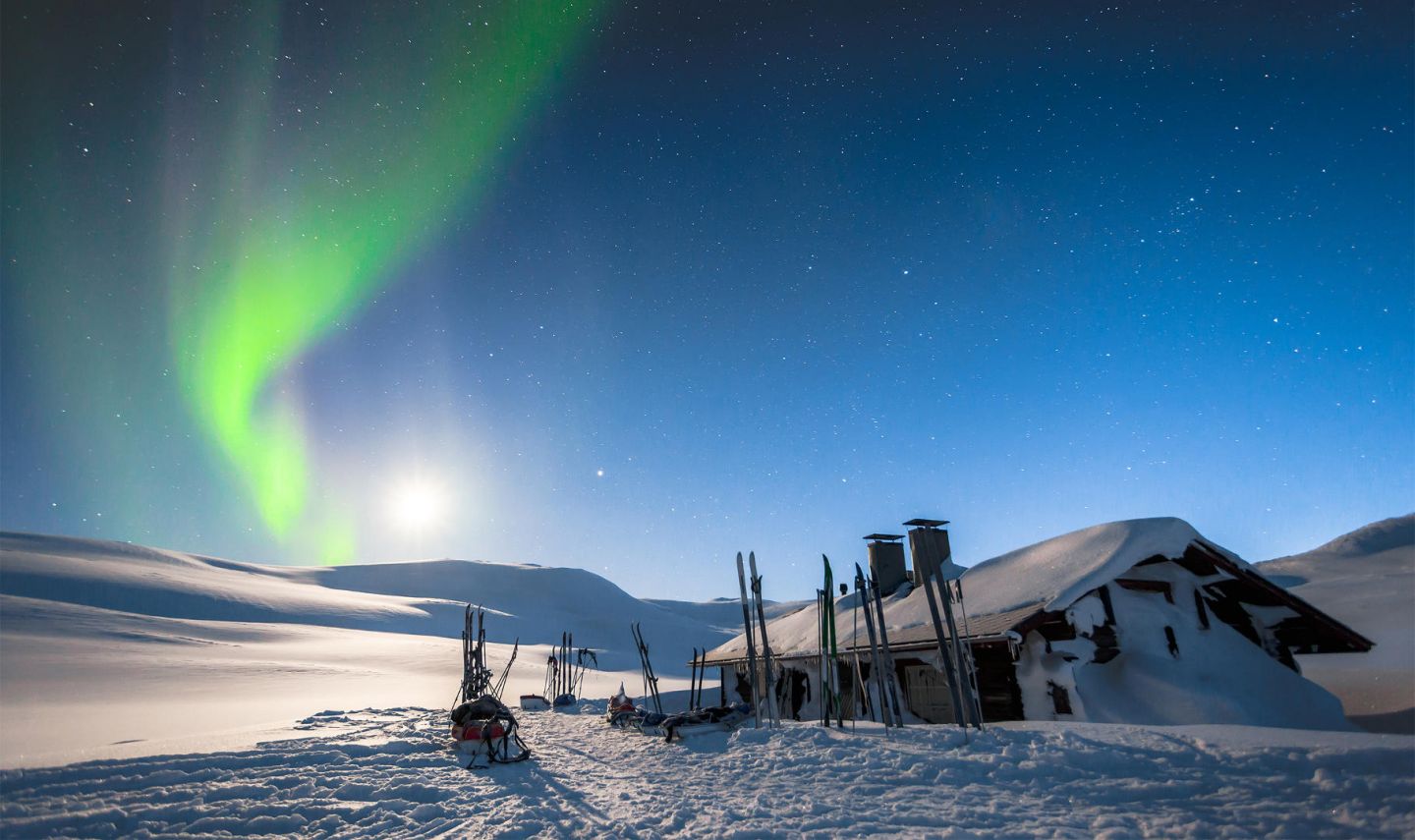 auroras over a snowy cabin in Lapland