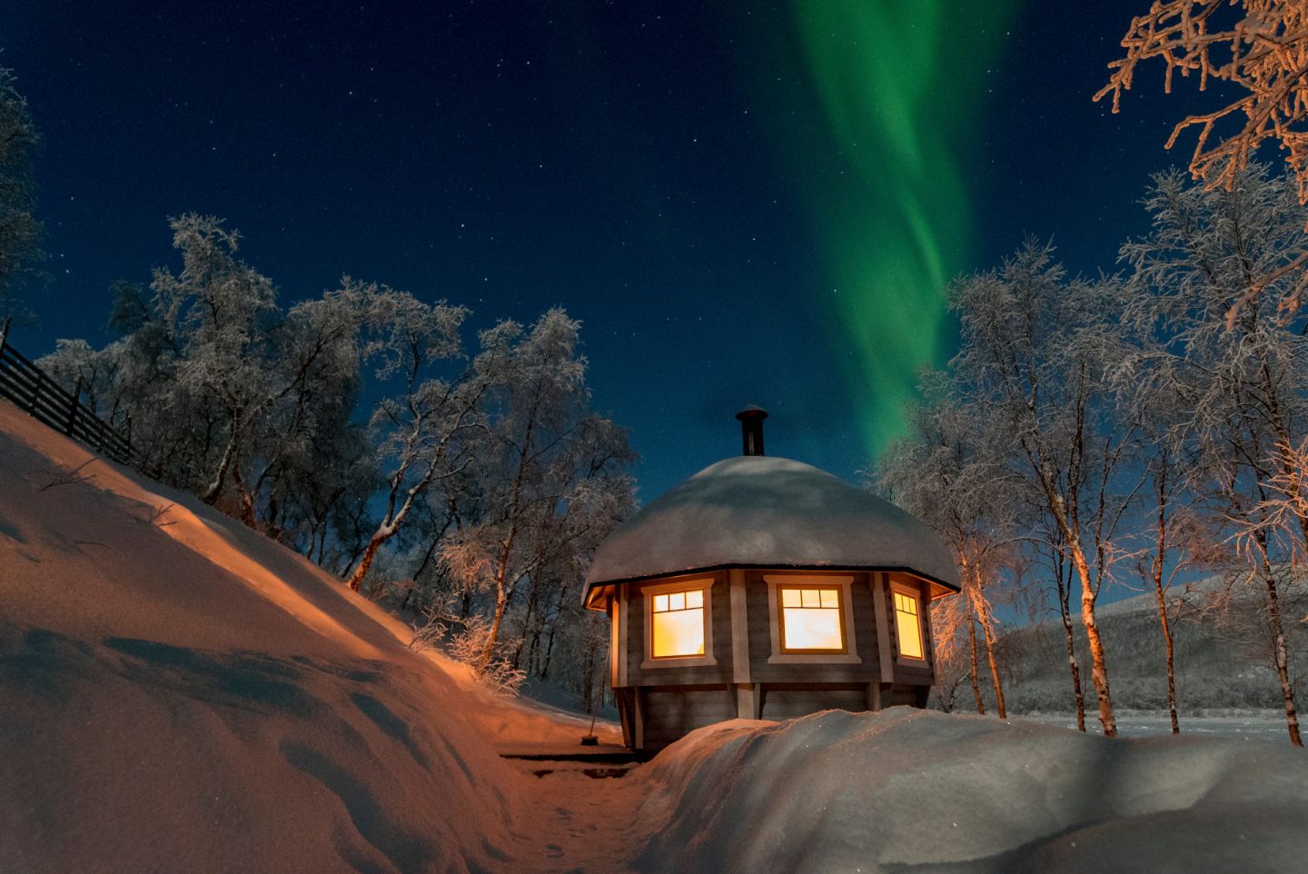 Northern Lights over a cabin at Aurora Holidays in Finnish Lapland