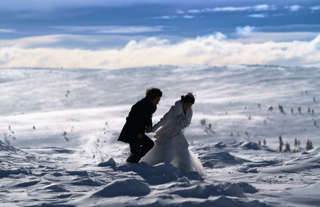 Wedding couple rushes across the deep snow in Lapland