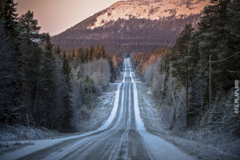 Snow dusted highway through the Arctic hills in Pelkosenniemi, Finland