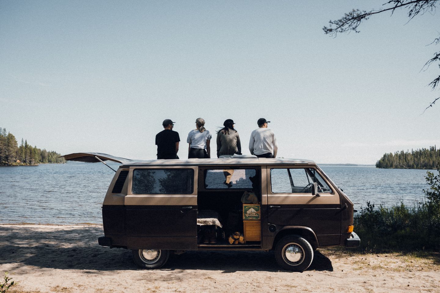 Group of Instagram Influencers sitting on top of the van staring at the lake ion Finnish Lapland