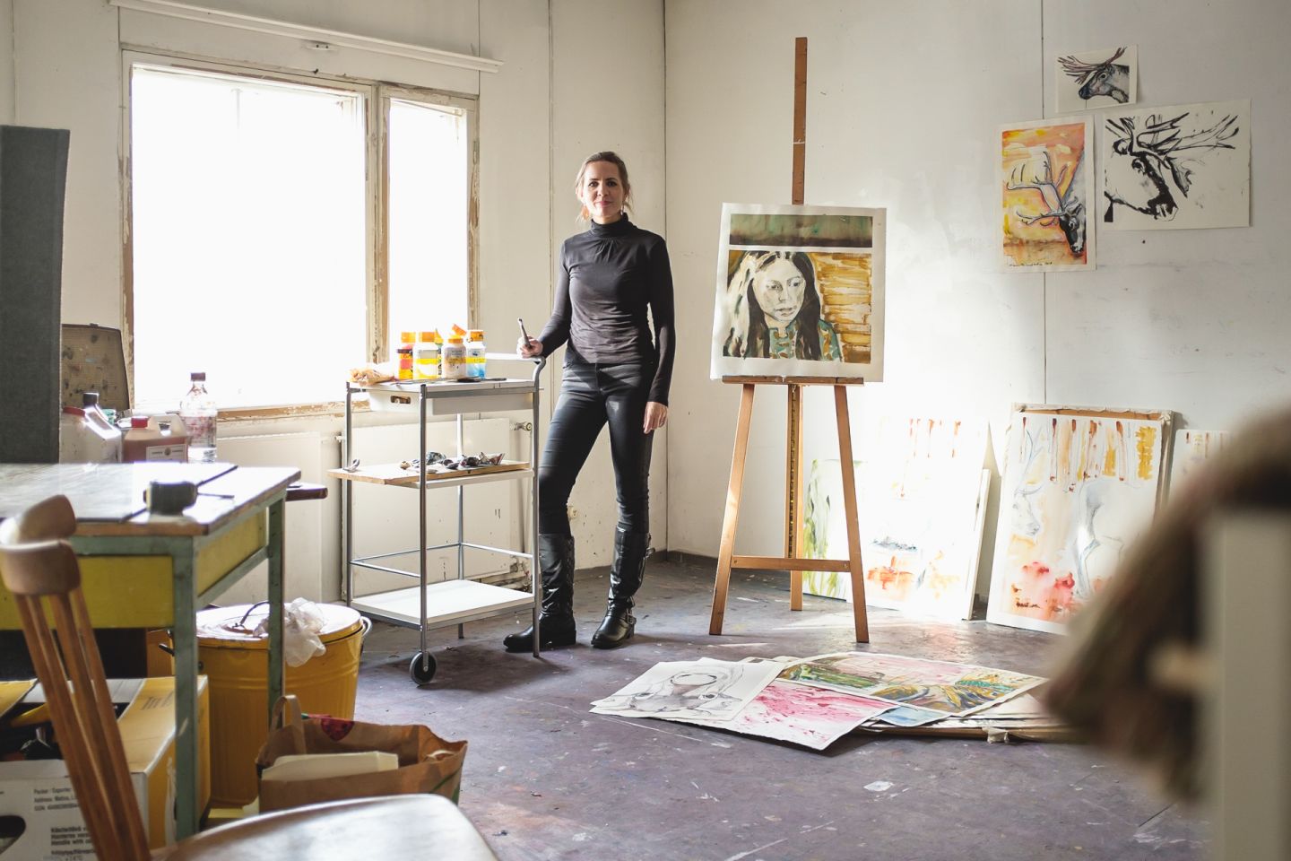 female artists standing in art studio surrounded by paintings