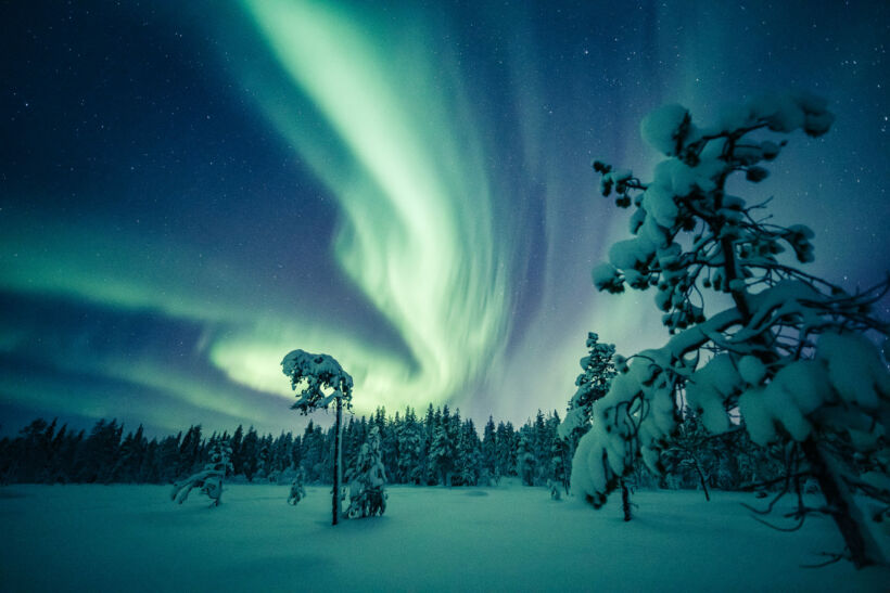 The Northern Lights (aurora borealis) over a snowy winter landscape in Finnish Lapland