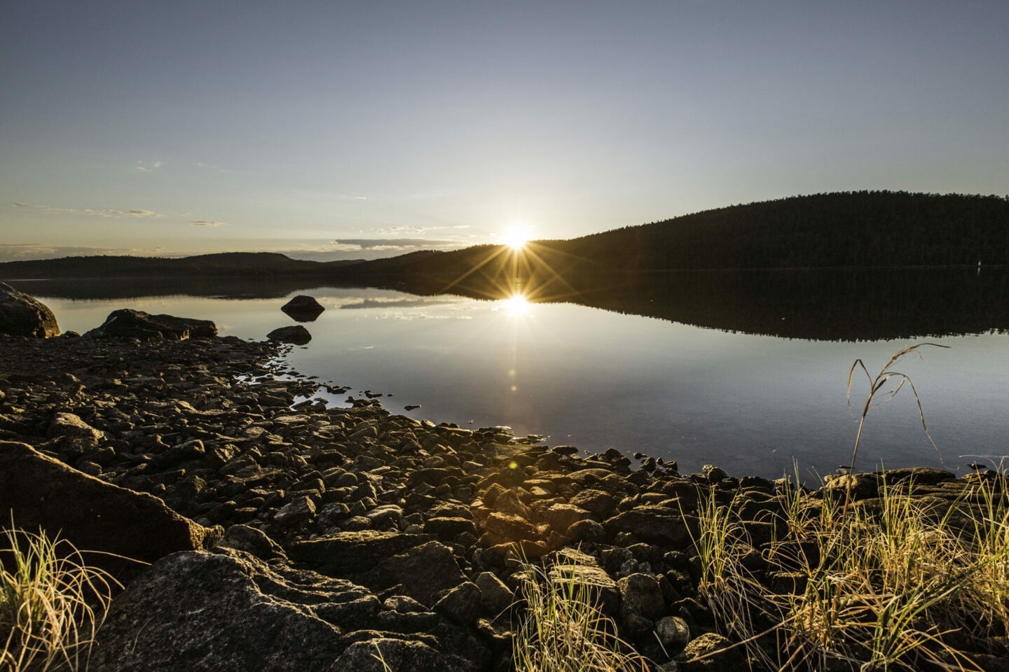 A dramatic sunset at the stony shore of Lake Inari in summer, a filming location in Finnish Lapland