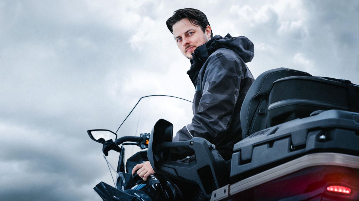 Henri Toppala sitting on a snowmobile and wearing snowmobiling gear from Bombardien BPR