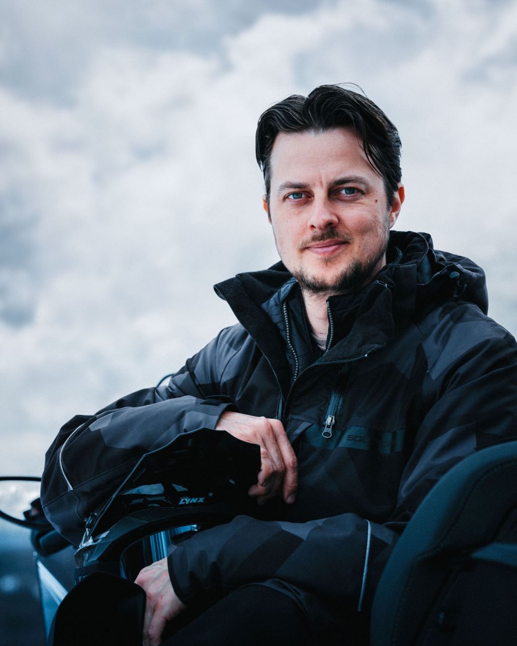 Henri Toppala sitting on a snowmobile and wearing snowmobiling gear from Bombardien BPR