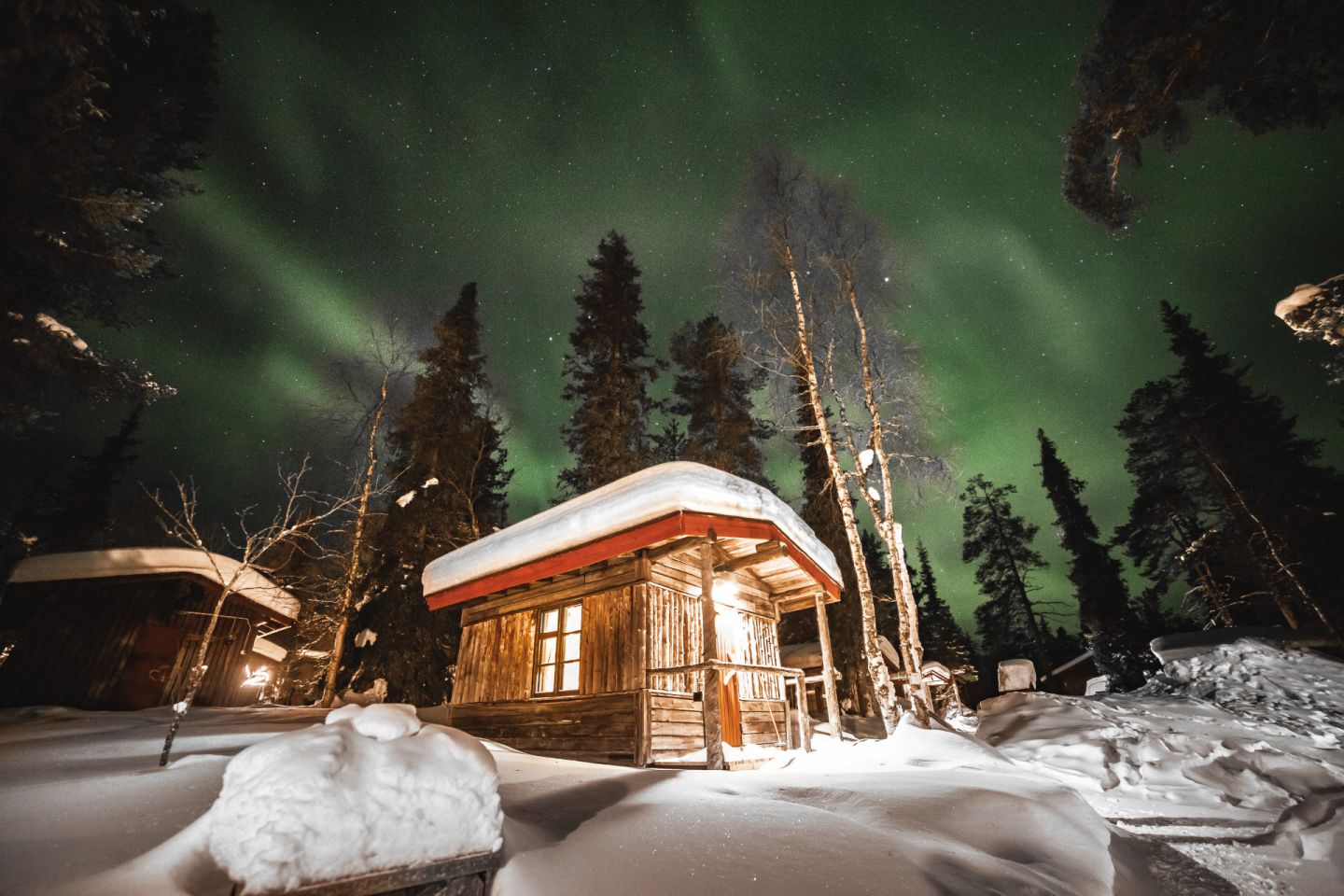 Northern Lights over a log cabin at Tankavaara Gold Village, a special winter accommodation in Sompio, Finland