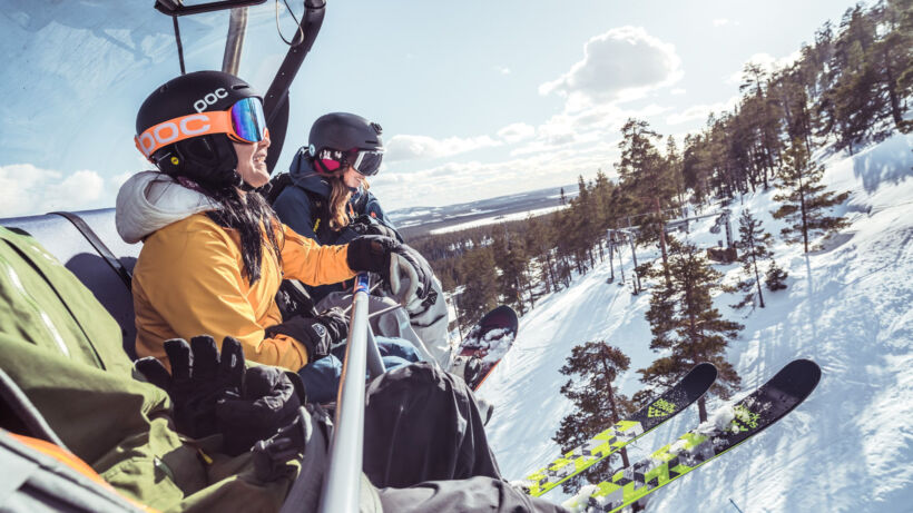 Downhill skiers are rising up to the top of Pyhätunturi on a chair lift.