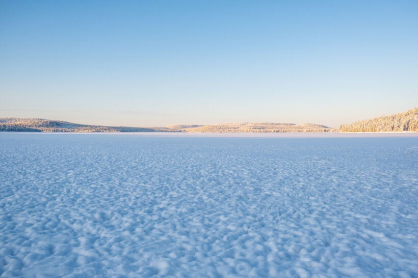 Sunny day at the frozen winter lake in Inari, a film location in Finnish Lapland