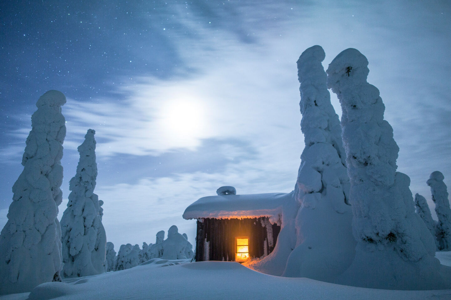 Snow-crowned trees surround a log cabin in Posio, a Finnish Lapland filming location