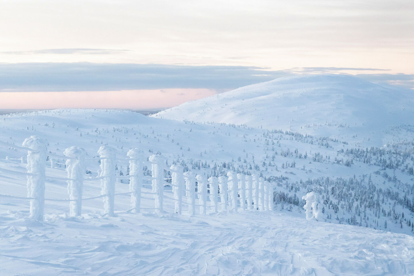 A fence outlined in snow atop Pyhätunturi, a filming location in Finnish Lapland